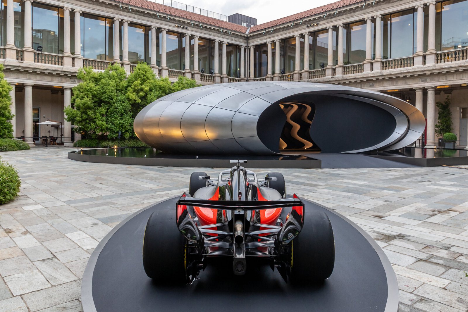 Rear view of the Audi Formula 1 show car Audi R26 displayed on a circular platform. In the background, Audi’s installation “Origin” shown at Milan Design Week 2026.