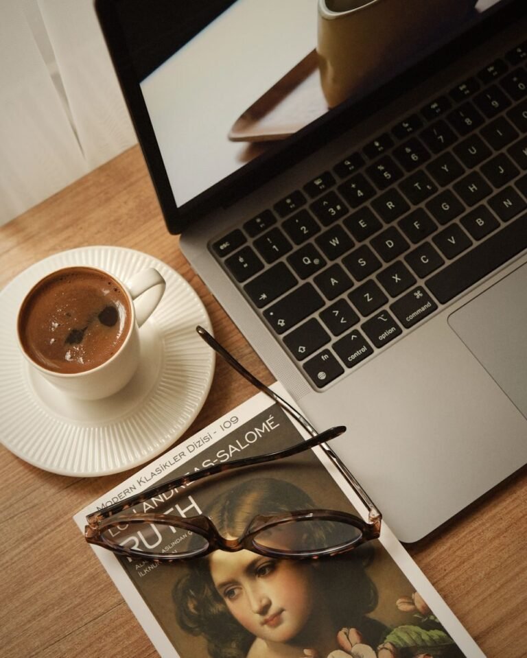 A serene workspace featuring coffee, a laptop, and a book on a wooden desk.