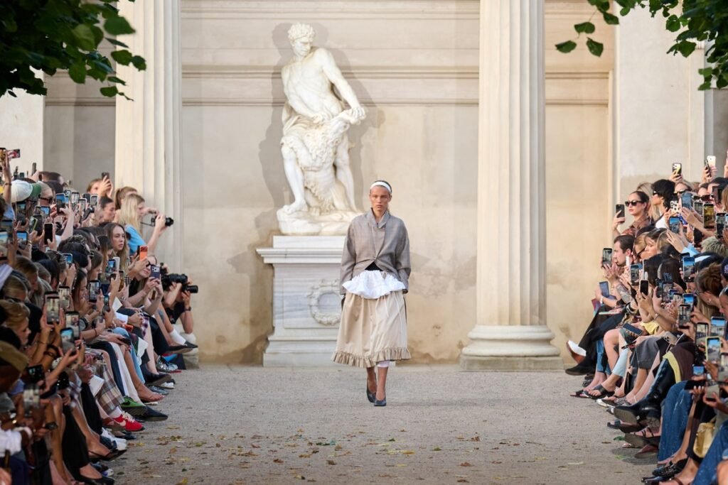 The open-air show in the King's Garden, a formal, historic Copenhagen setting, featured models alongside friends of the house and new faces, making the presentation feel like an expanded version of the brand's own community.