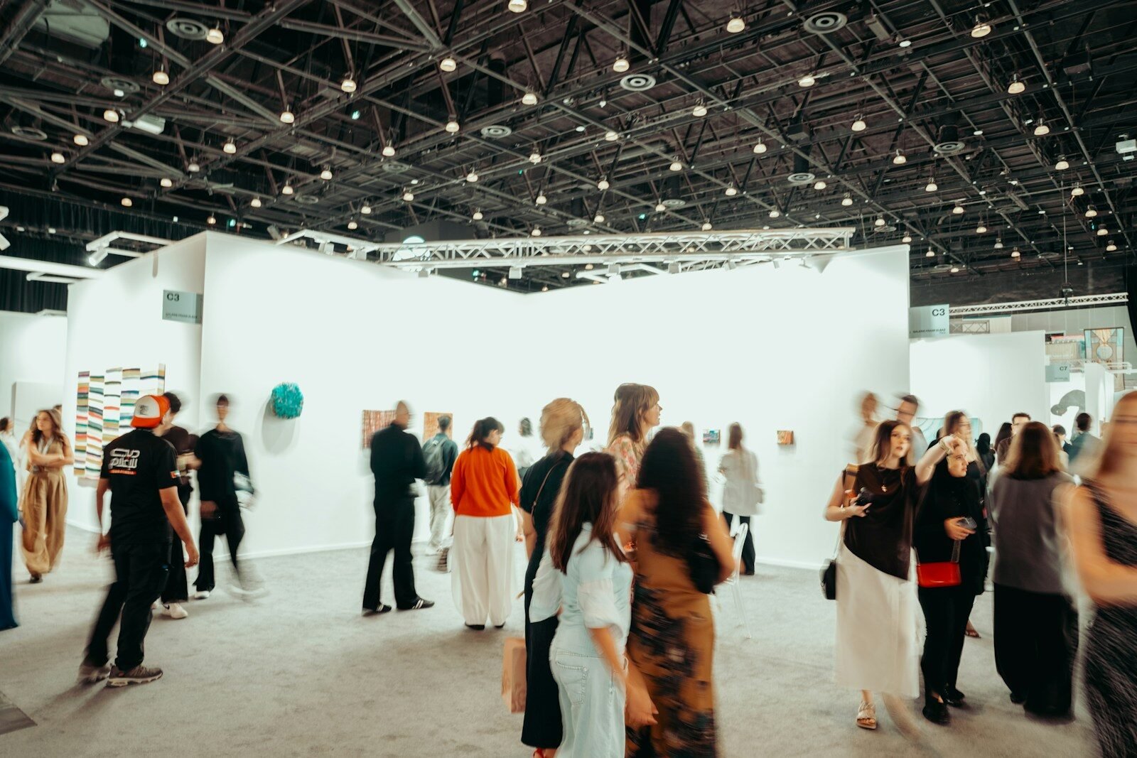 People browse art exhibits in a large, well-lit gallery